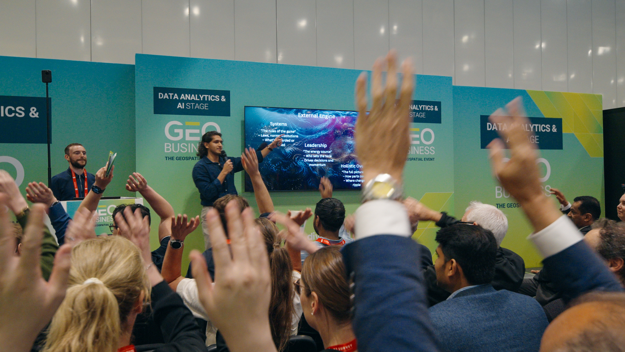 Audience members taking part with raised hands at GEO Business